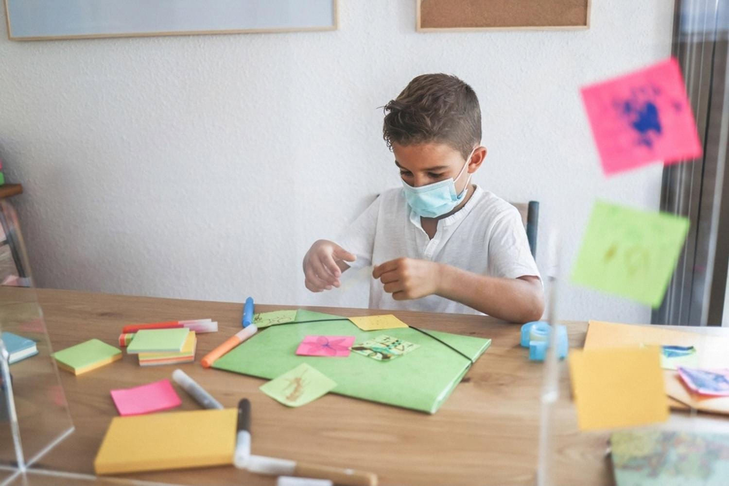 Boy at a craft desk in the UAE with markers, sticky notes and paper